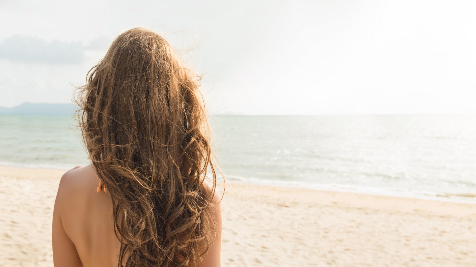 Beautiful independent woman looking at the view in tropical beach during summer