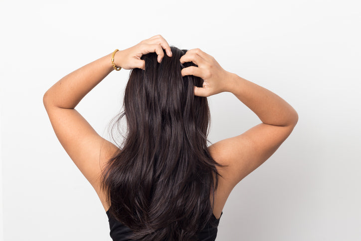 back view of a woman with her hand on her scalp