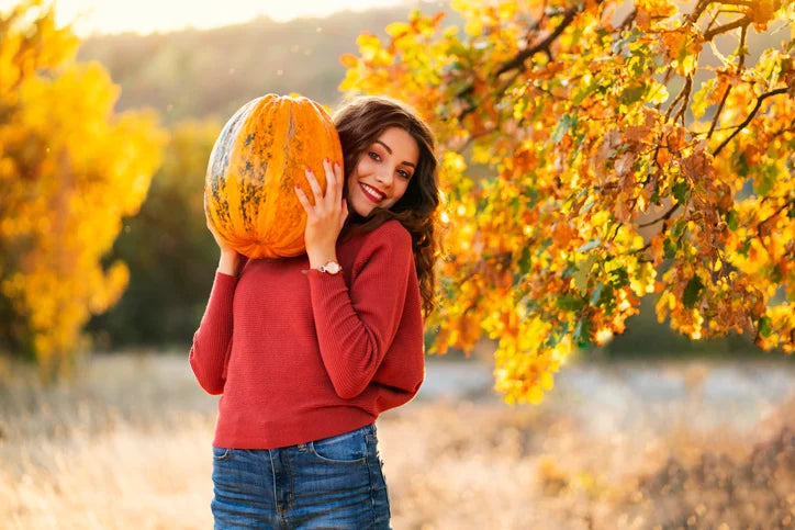 woman smiling holding a pumpkin outdoor
