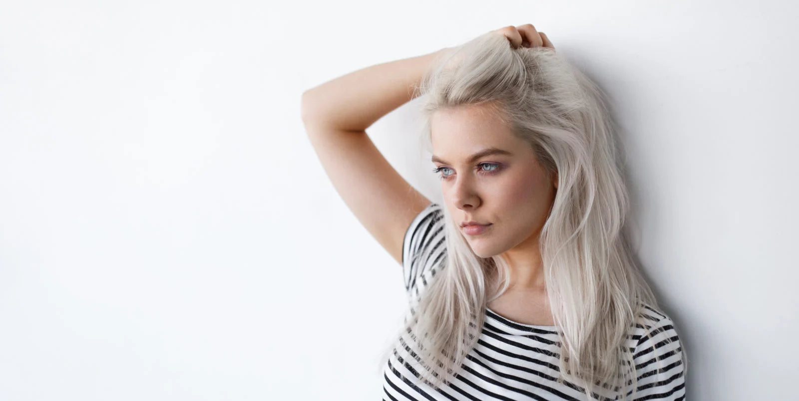 woman with blond hair leaning against the wall with her hand on her head