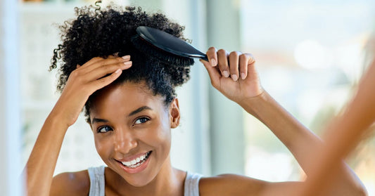 woman brushing her curly hair while looking at the mirror