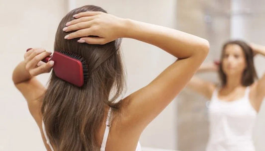 woman brushing her hair while looking at the mirror