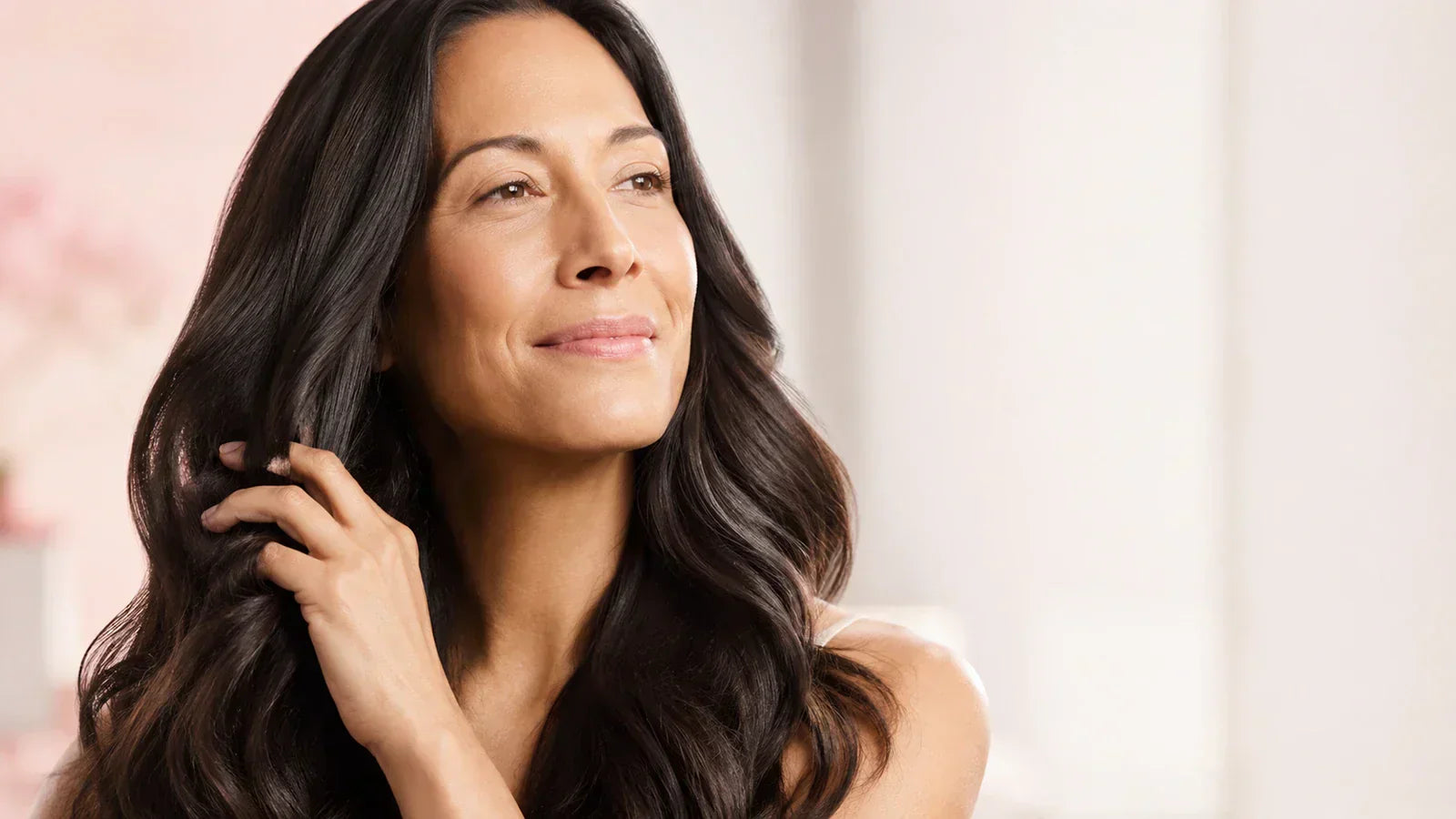 Woman with long, healthy-looking dark hair touching her hair