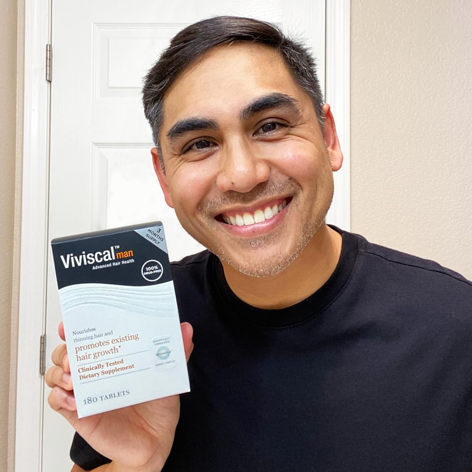 man smiling holding Viviscal man hair growth supplements
